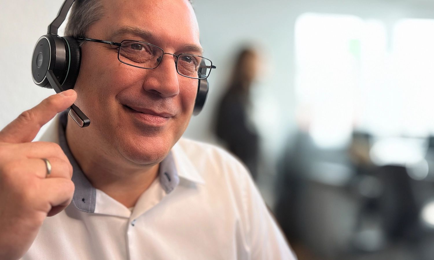 Ein freundlich wirkender Support-Mitarbeiter mit Headset.