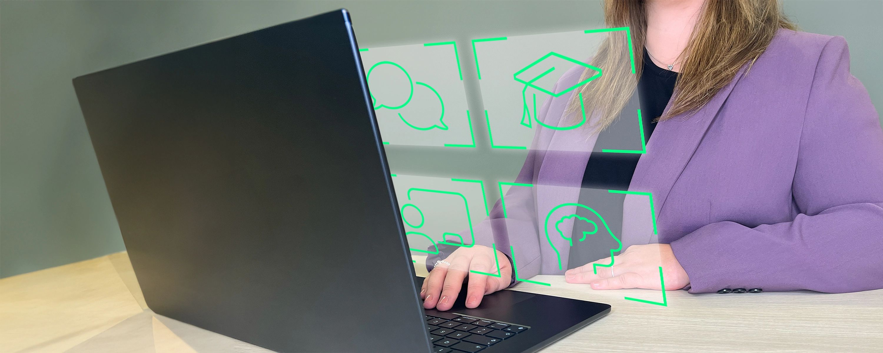 Mitarbeiterin arbeitet an einem Laptop, über dem holografische Icons für E-Learning, Schulung, Kommunikation und Wissen dargestellt sind.