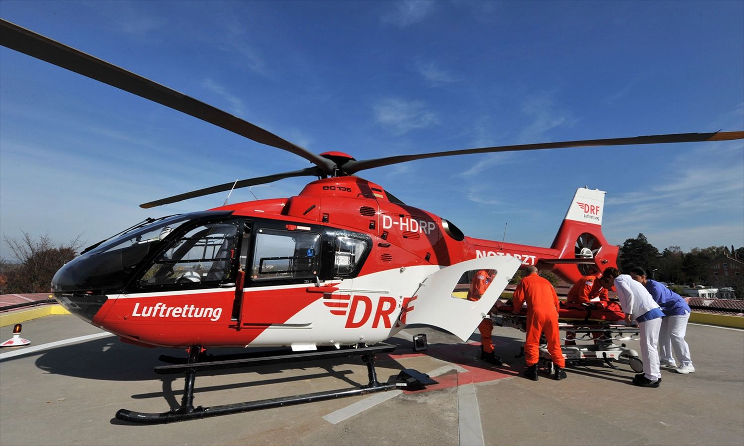 DRF Luftrettungsteam bereitet einen roten Rettungshubschrauber für den Einsatz vor – schnelle medizinische Hilfe und moderne Notfallversorgung aus der Luft.