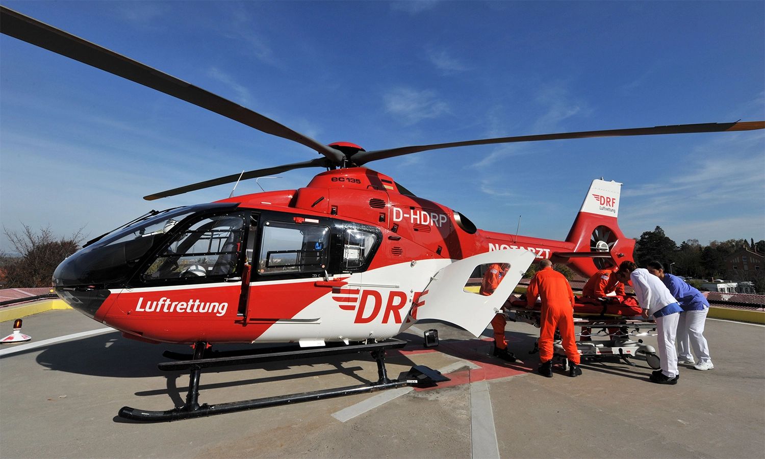 Mediziner und Piloten der DRF Luftrettung bereiten einen roten Rettungshubschrauber für den Patiententransport vor – schnelle Notfallhilfe und höchste Einsatzbereitschaft.