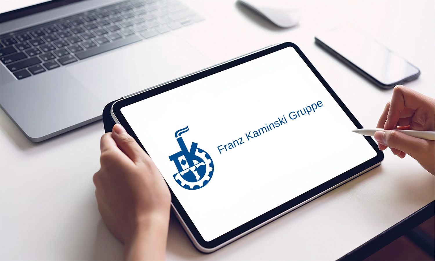 Logo der Franz Kaminski Gruppe auf dem Display eines Tablets – Symbol für modernes Industrieunternehmen mit Tradition in Waggonbau und Instandhaltungstechnik.