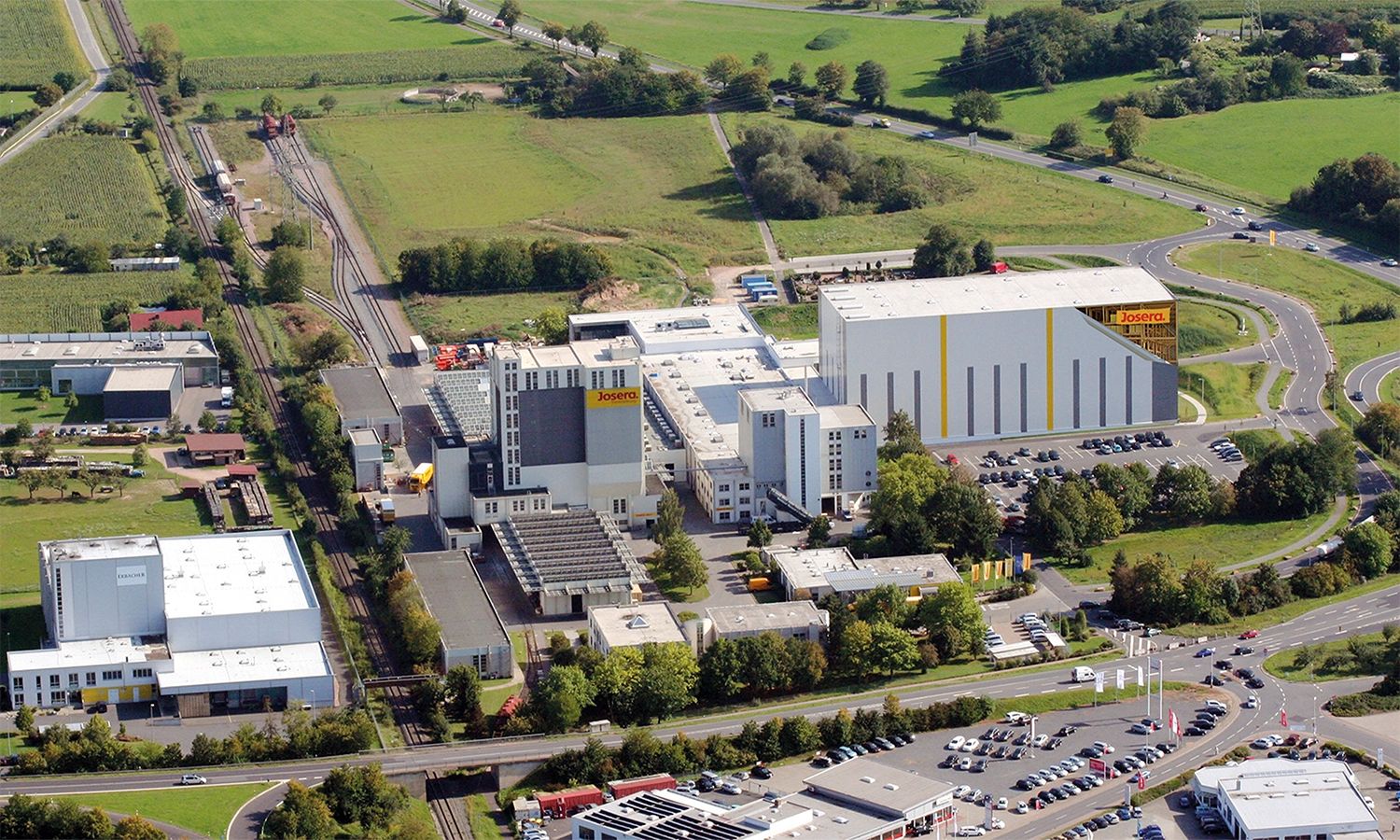 Luftaufnahme des Josera‑Firmengeländes – moderner Produktions‑ und Logistikstandort für nachhaltige Tiernahrung inmitten grüner Landschaft.