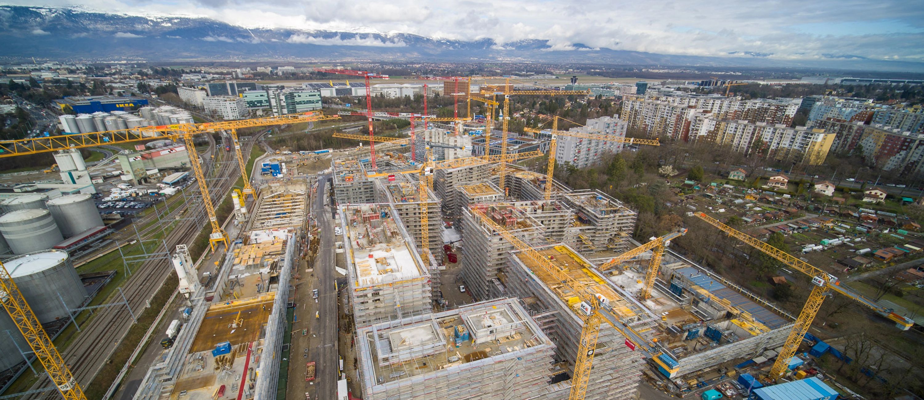 Großbaustelle mit mehreren Kränen und Gebäudekomplexen – Luftaufnahme eines urbanen Bauprojekts mit Gebäudetechniklösungen von Roth.