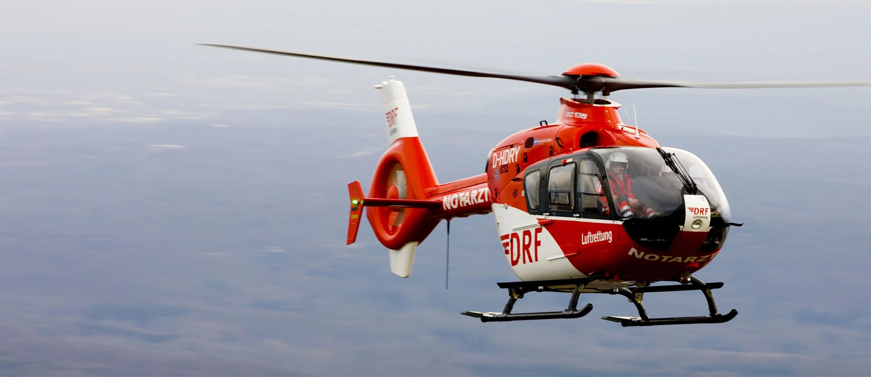 Roter DRF-Luftrettungshubschrauber im Flug – schnelle und zuverlässige Notfallrettung mit moderner Luftfahrttechnologie.