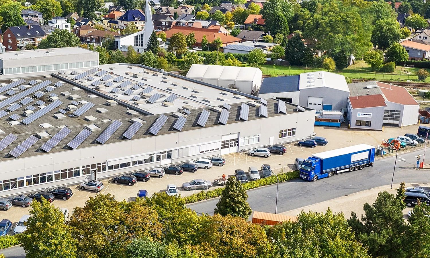 Produktionsgebäude der Firma Herzog – moderne Industriehalle mit Solaranlage auf dem Dach, Symbol für nachhaltige Fertigung, Energieeffizienz und technologische Innovation.