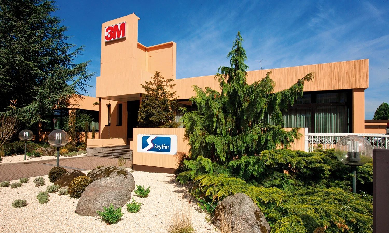 Firmensitz von Seyffer mit 3M‑Partnerlogo – modernes Gebäude mit gepflegter Gartenanlage, Sitz des Verbindungstechnik‑ und Klebespezialisten Seyffer.