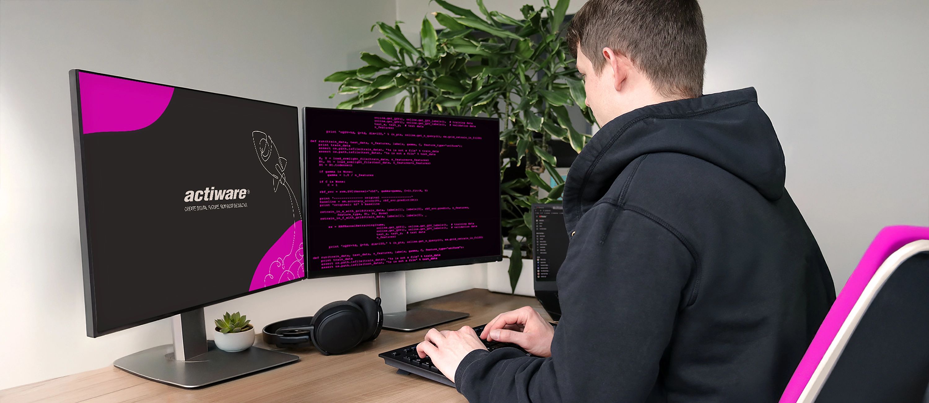 Mitarbeiter sitzt vor Bildschirmen und programmiert.