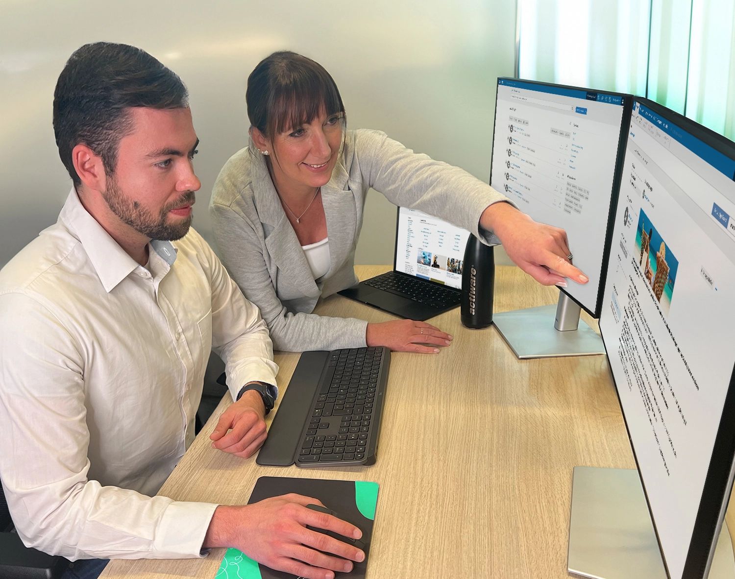 Eine Mitarbeiterin erklärt ihrem Kollegen die Wissensmanagement-Lösung ELO Knowledge und zeigt dabei auf eine Funktion auf dem Bildschirm.