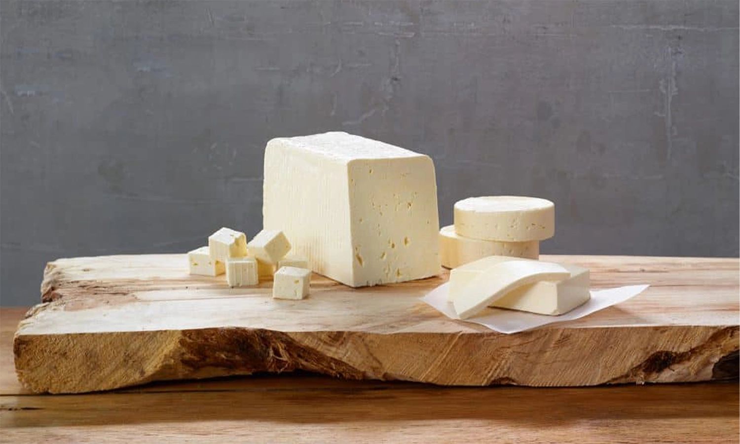 Rücker‑Fetakäse auf rustikalem Holzbrett – verschiedene Schnittformen von norddeutschem Qualitätskäse des traditionellen Molkereiunternehmens.