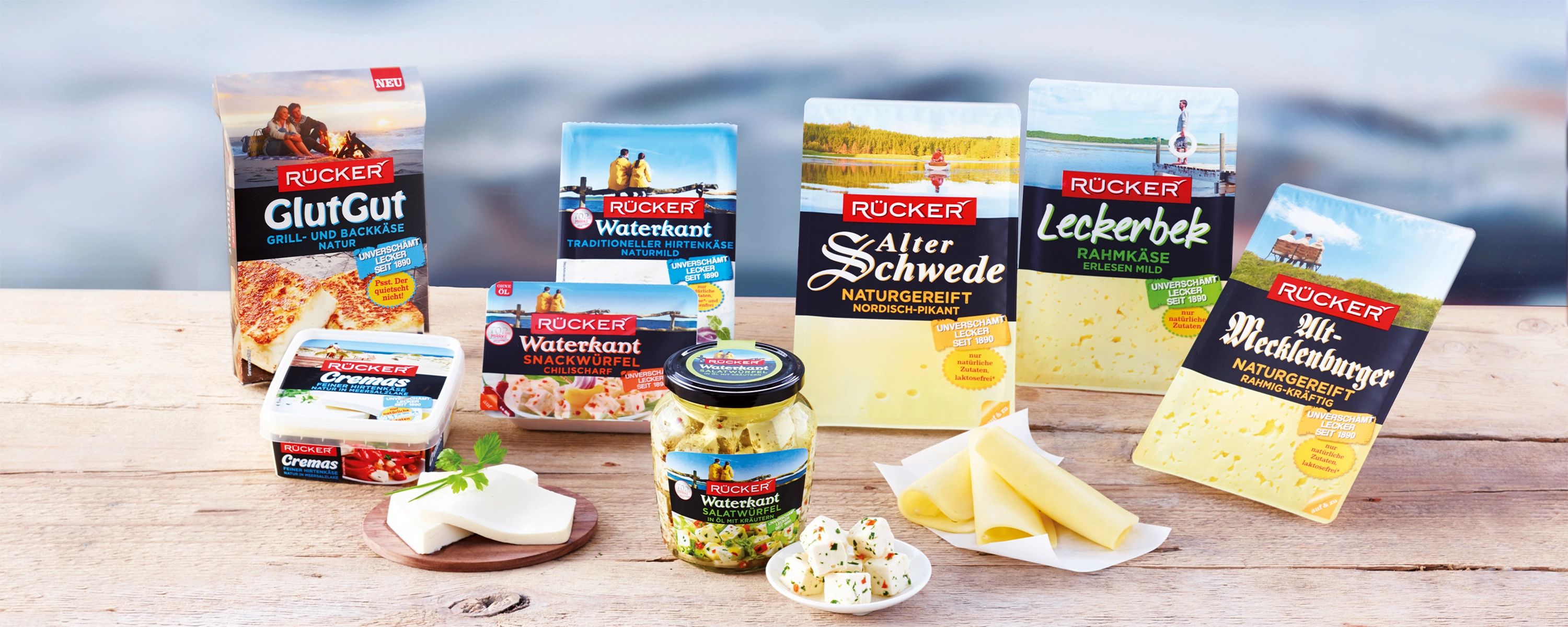 Sortiment verschiedener Rücker‑Käseprodukte auf Holztisch – norddeutsche Spezialitäten wie Alter Schwede, Waterkant und Alt‑Mecklenburger zeigen die Vielfalt der Molkerei Rücker.
