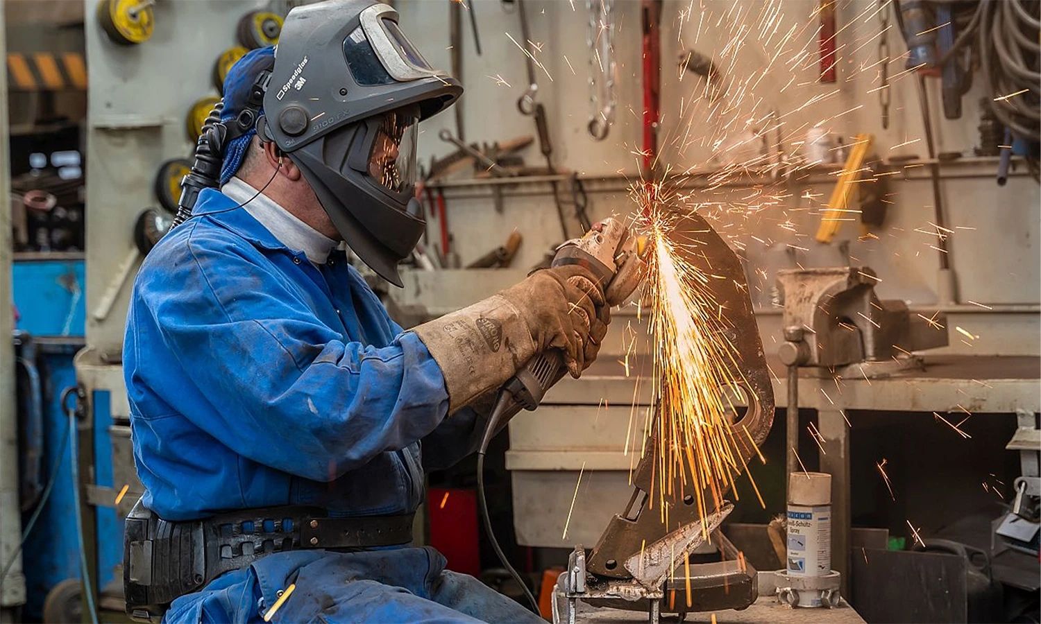 Schweißer der Franz Kaminski Waggonbau GmbH bearbeitet Metallteil mit Winkelschleifer – präzise Handwerksarbeit und Instandhaltung von Eisenbahnkomponenten.