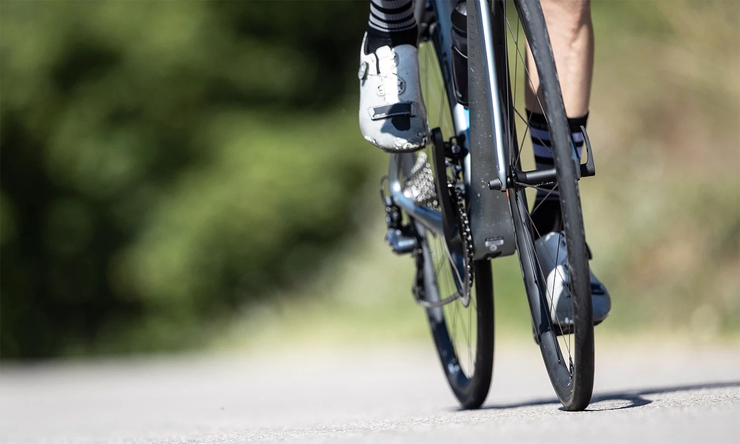 Rennradfahrer auf Landstraße – Detailaufnahme des Hinterrads mit Schwalbe‑Reifen, Symbol für Geschwindigkeit, Kontrolle und Performance im Radsport.